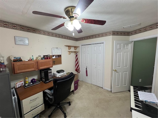home office with a textured ceiling, visible vents, a ceiling fan, and light carpet