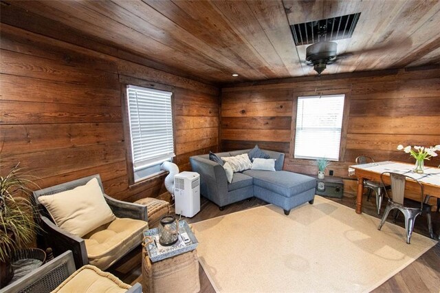 living area featuring wood-type flooring, ceiling fan, wooden ceiling, and wooden walls