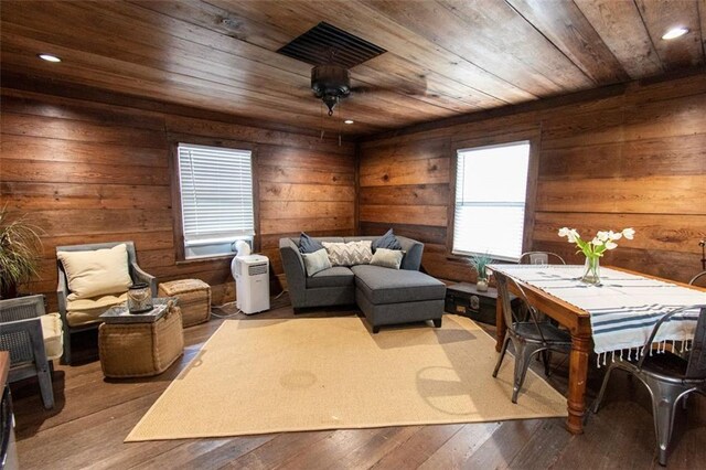 living area with light wood-type flooring, wooden ceiling, and wooden walls