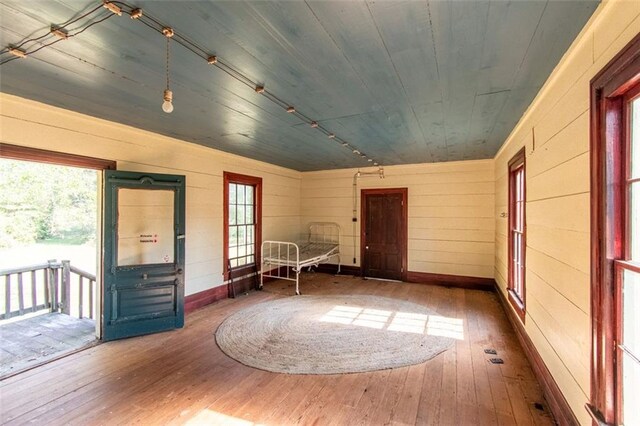 interior space with wooden ceiling, wooden walls, dark hardwood / wood-style flooring, and plenty of natural light