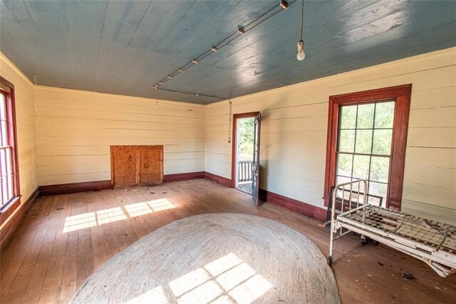 unfurnished bedroom featuring wooden walls, dark hardwood / wood-style floors, wood ceiling, and multiple windows