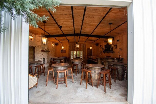 dining room featuring concrete floors, wood walls, and wooden ceiling