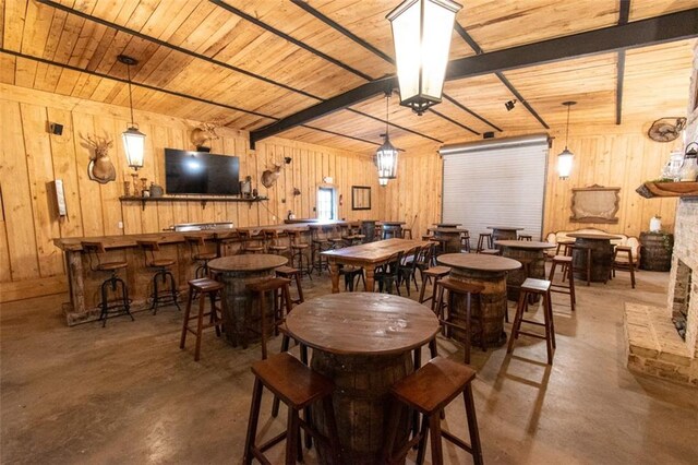 dining area featuring wood ceiling, wooden walls, and concrete flooring