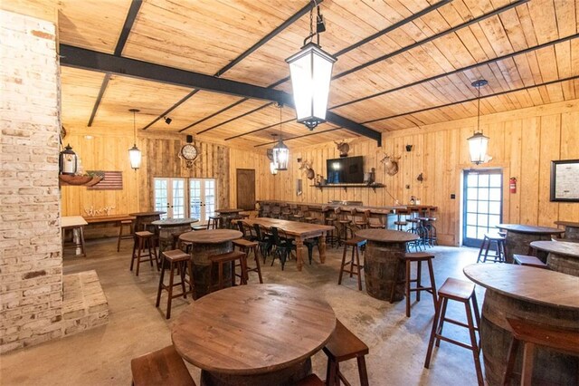 dining room featuring beamed ceiling, wooden walls, and wooden ceiling