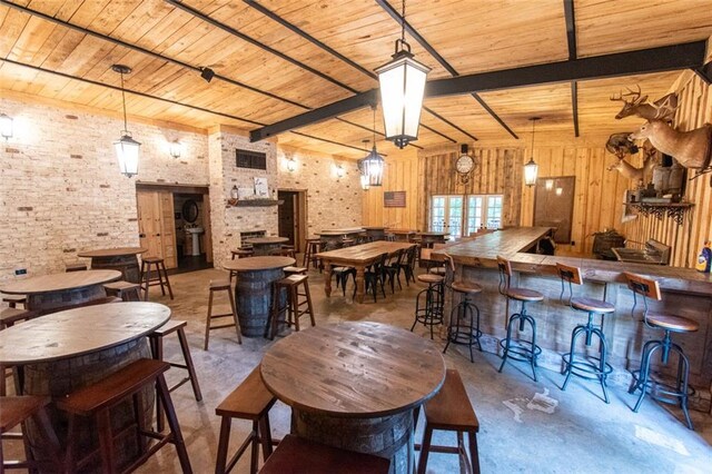 dining space featuring wood ceiling, beam ceiling, wood walls, concrete flooring, and brick wall