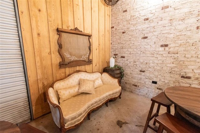 living area with wooden walls and brick wall