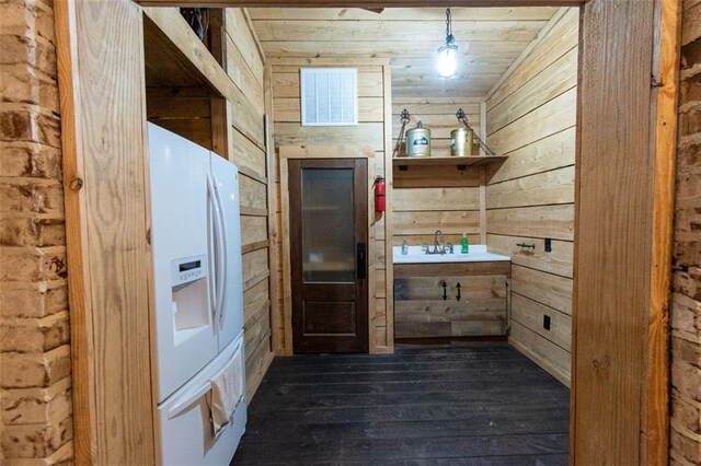 kitchen featuring pendant lighting, wood ceiling, wood walls, white refrigerator with ice dispenser, and dark hardwood / wood-style flooring