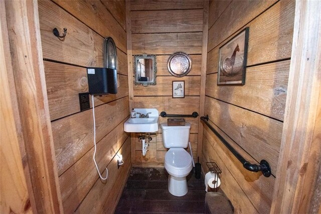 bathroom featuring wooden walls, toilet, and sink