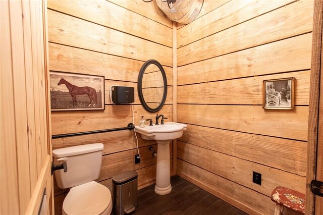 bathroom featuring wood-type flooring, wood walls, and toilet