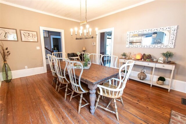 dining area with ornamental molding, a notable chandelier, and dark hardwood / wood-style flooring