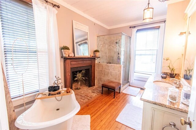 bathroom with independent shower and bath, hardwood / wood-style flooring, vanity, and ornamental molding