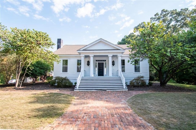 neoclassical home featuring a front lawn