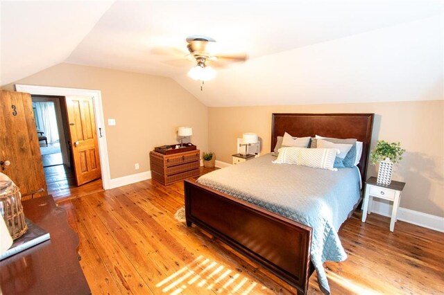 bedroom with ceiling fan, hardwood / wood-style flooring, and vaulted ceiling