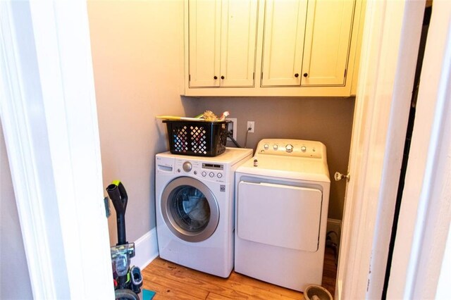 laundry area featuring cabinets, light wood-type flooring, and independent washer and dryer