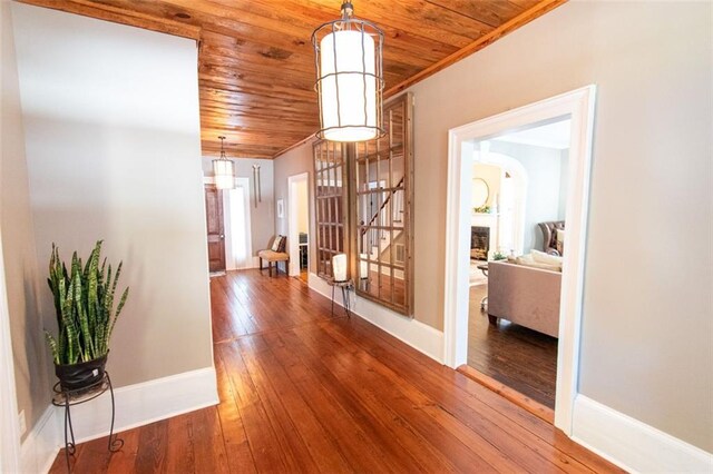 hallway with crown molding, wood ceiling, and hardwood / wood-style flooring