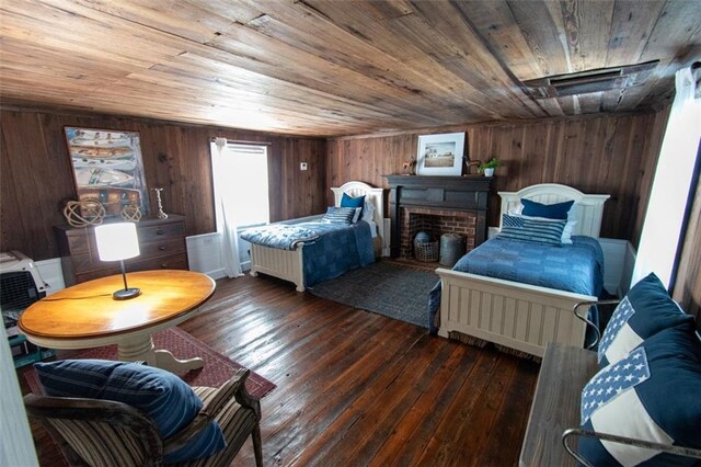 bedroom with a brick fireplace, wood ceiling, dark hardwood / wood-style floors, and wood walls