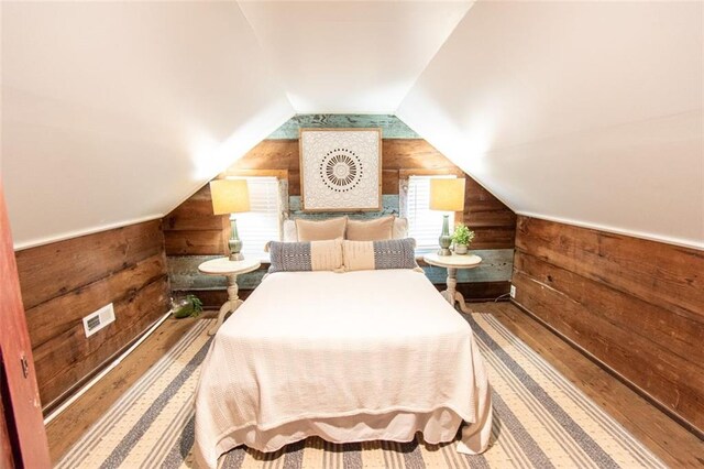 bedroom featuring lofted ceiling and wood walls