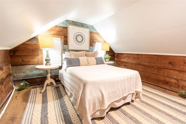 bedroom featuring wooden walls, vaulted ceiling, and hardwood / wood-style floors