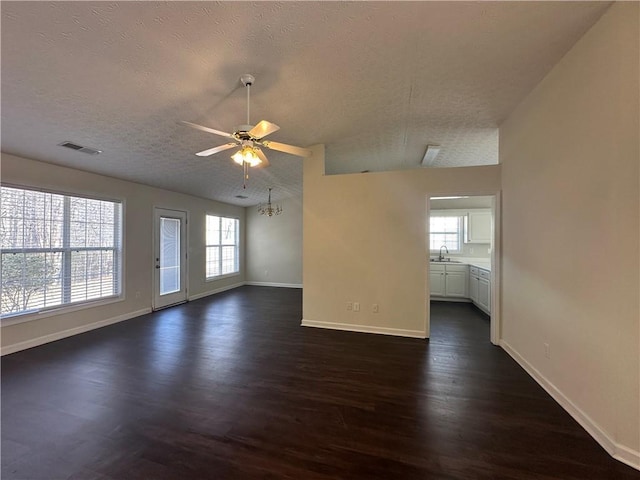 unfurnished living room featuring visible vents, dark wood finished floors, vaulted ceiling, a textured ceiling, and a sink