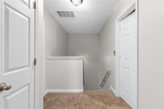 stairs with carpet floors and a textured ceiling