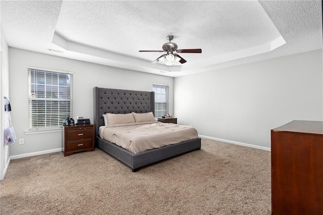 bedroom featuring light carpet, a raised ceiling, and ceiling fan