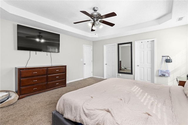 bedroom with a tray ceiling, ceiling fan, and carpet flooring