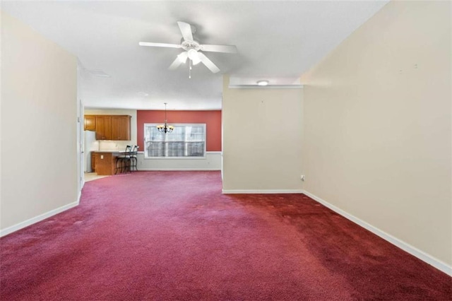 unfurnished living room with ceiling fan with notable chandelier and dark colored carpet