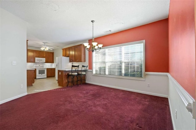 kitchen with ceiling fan with notable chandelier, pendant lighting, decorative backsplash, light carpet, and white appliances