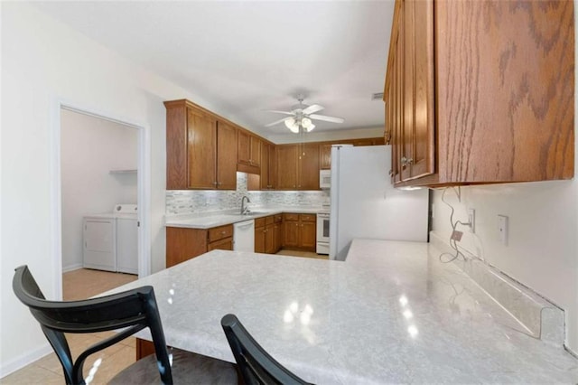 kitchen with tasteful backsplash, separate washer and dryer, ceiling fan, kitchen peninsula, and white appliances