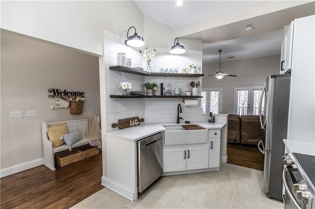 kitchen featuring open shelves, a sink, white cabinetry, stainless steel appliances, and vaulted ceiling