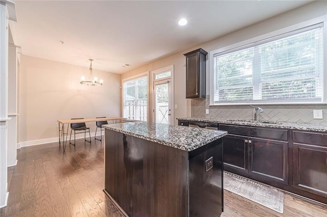 kitchen featuring dark brown cabinetry, tasteful backsplash, decorative light fixtures, dark hardwood / wood-style floors, and a kitchen island