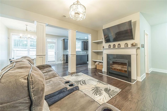 living room featuring dark wood-type flooring, an inviting chandelier, and ornate columns