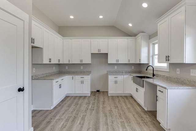 kitchen featuring recessed lighting, light wood-style flooring, white cabinetry, a sink, and light stone countertops