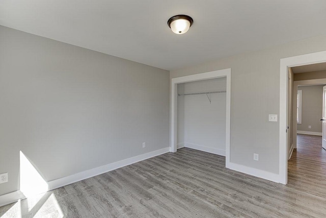 unfurnished bedroom with light wood finished floors, a closet, and baseboards