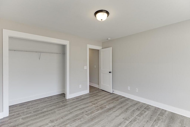 unfurnished bedroom with a closet, wood finished floors, and baseboards