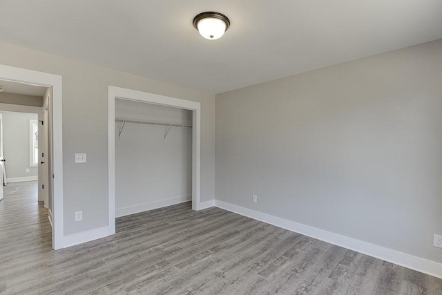 unfurnished bedroom with a closet, baseboards, and wood finished floors