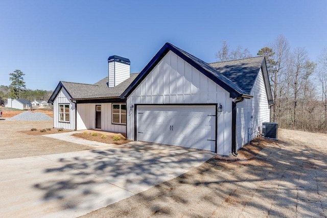 modern farmhouse featuring a chimney, central air condition unit, board and batten siding, a garage, and driveway