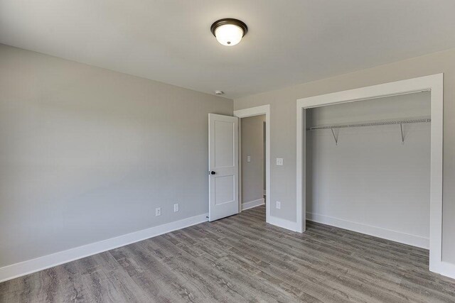 unfurnished bedroom with a closet, wood finished floors, and baseboards