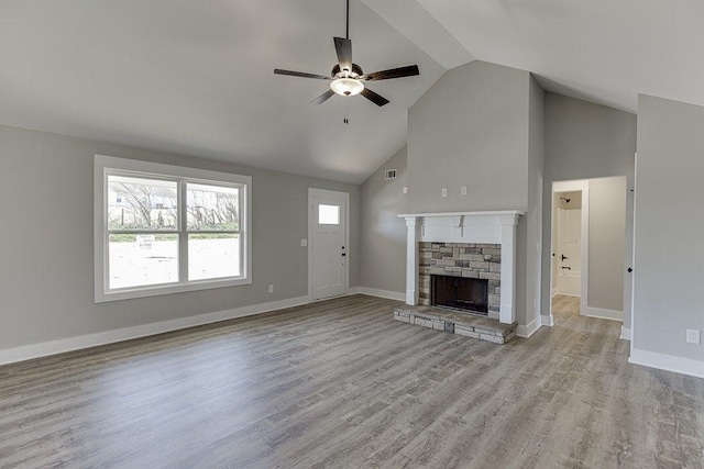 unfurnished living room with baseboards, wood finished floors, and a stone fireplace