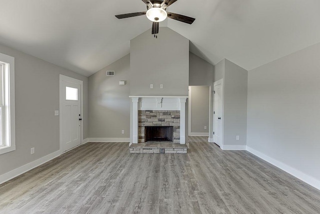 unfurnished living room with ceiling fan, high vaulted ceiling, a fireplace, wood finished floors, and baseboards