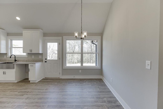 kitchen with lofted ceiling, light wood-style flooring, white cabinets, and a sink