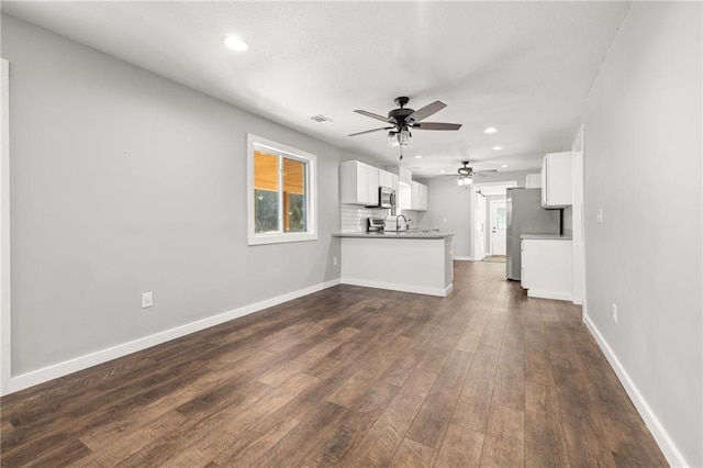 unfurnished living room featuring dark hardwood / wood-style flooring, ceiling fan, and sink