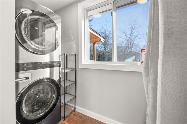 laundry area featuring stacked washer and dryer and dark wood-type flooring