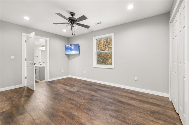 unfurnished bedroom with ceiling fan, dark hardwood / wood-style floors, ensuite bathroom, and a closet