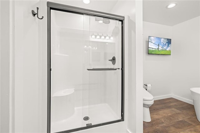 bathroom featuring toilet, an enclosed shower, and wood-type flooring