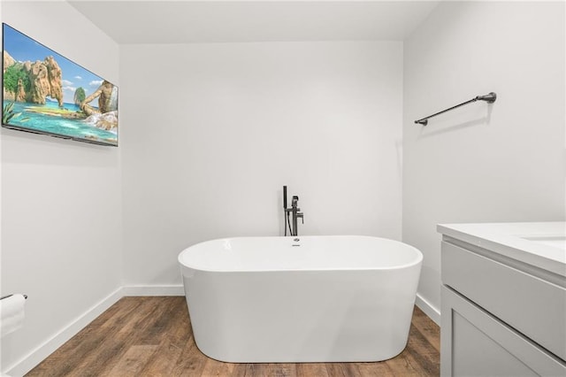 bathroom with hardwood / wood-style flooring, vanity, and a bath