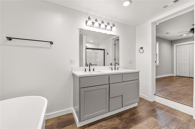 bathroom featuring ceiling fan, vanity, wood-type flooring, and plus walk in shower