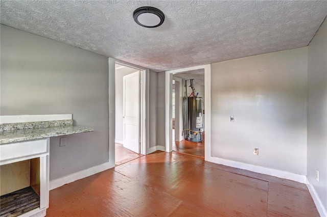 unfurnished living room with gas water heater, baseboards, a textured ceiling, and wood finished floors