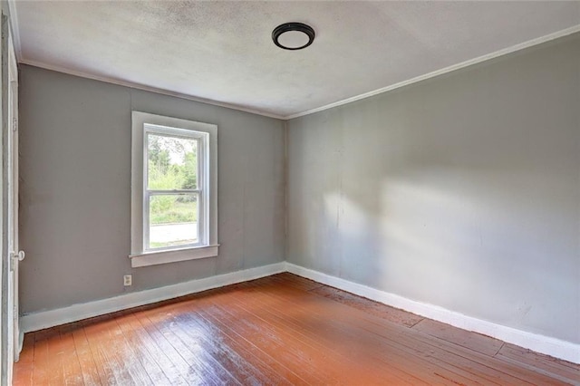 unfurnished room with wood-type flooring, baseboards, and crown molding