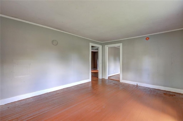 empty room featuring baseboards, wood finished floors, and crown molding
